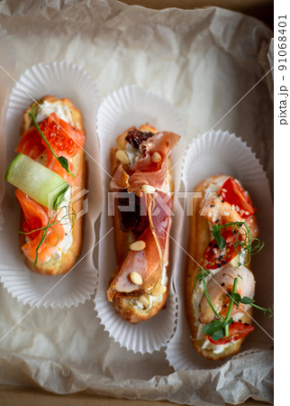 Eclairs with salmon, fresh vegetables and herbs, gourmet snacks. 91068401