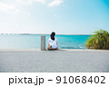 沖縄に一人旅をする女子が海を眺める 91068402