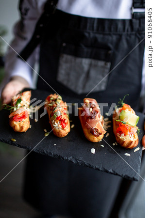Eclairs with salmon, fresh vegetables and herbs, gourmet snacks. 91068405