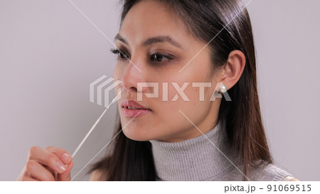Young woman takes a sample from her nose for a corona test Young woman takes a sample from her nose for a corona test 91069515