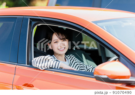 笑顔で車の運転をする若い女性 91070490