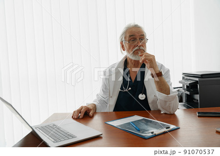 Senior healthcare worker doing some paperwork and using laptop while working at doctor's office 91070537