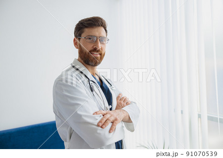 Portrait of smiling doctor in glasses standing in medicine clinic hall and looking camera 91070539