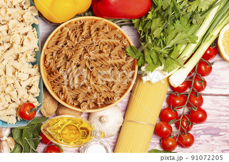 Italian pasta with vegetables, olive oil, spices on a wooden background, top view 91072205