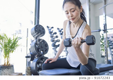 スポーツジムでトレーニングをする若い女性 91072283