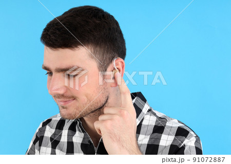Young man with hearing aid on blue background Young man with hearing aid on blue background 91072887