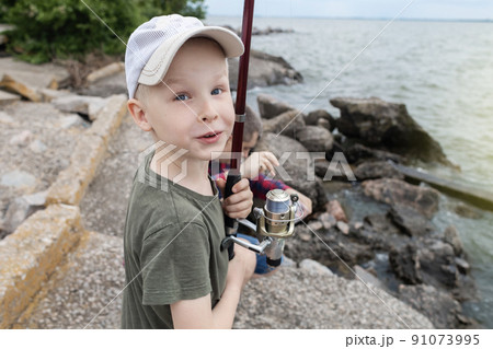 Father and son fishing. Dad shows his son how to hold the spinning and spin the reel. Fishing training on a pond or river. Caring parent concept. 91073995
