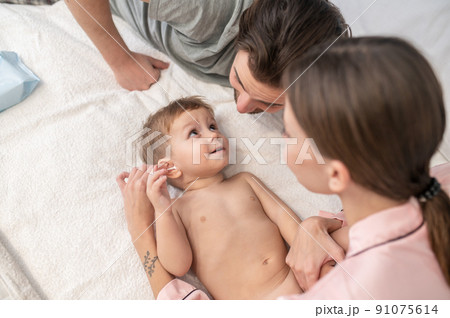 Woman touching ear of child looking at dad 91075614