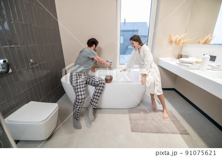 Man and woman crouching on bathtub bathing child 91075621