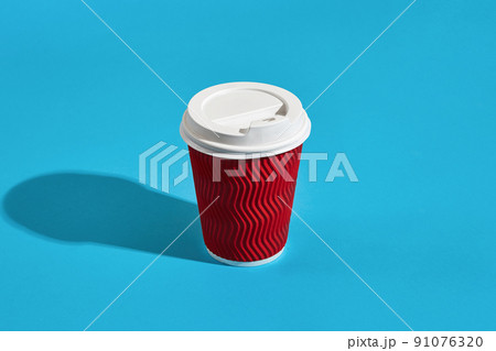 Hot coffee in red paper cup with white lid on blue background wi 91076320
