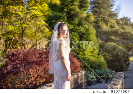White Caucasian Adult Woman in a Wedding Dress standing outside in nature. White Caucasian Adult Woman in a Wedding Dress standing outside in nature. 91077607