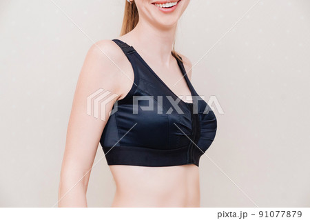 A young woman in black compression underwear after mammoplasty. 91077879