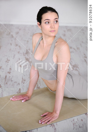 A young beautiful woman practices yoga in a modern studio, stands in a dog pose. A young beautiful woman practices yoga in a modern studio, stands in a dog pose. 91078634
