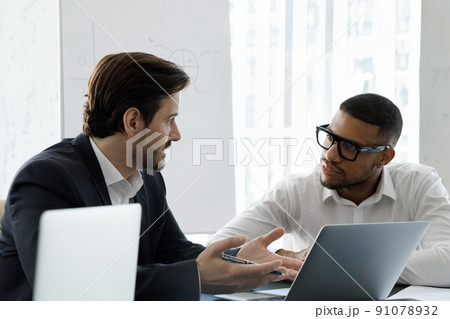 Multi racial businessmen talking during formal meeting in modern office 91078932