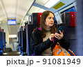 Female traveler using mobile phone while riding train 91081949
