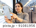 Woman taking pictures with her smartphone during train ride 91081956