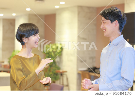 3594_両手で高さ大きさを表現しながら打ち合わせる2人のビジネスパーソン2 91084170