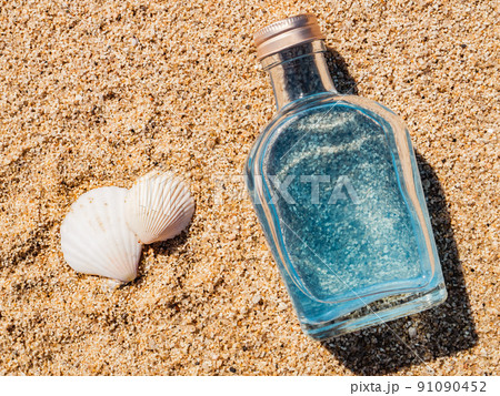 【ビーチ】海の砂浜の上のガラスボトルと貝殻 91090452