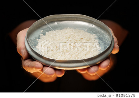 Hands holding a heap of dry rice grain on black background Hands holding a heap of dry rice grain on black background 91091579