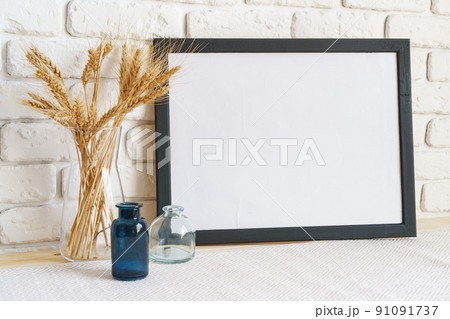 Vase with ears of wheat and photo frames against brick wall Vase with ears of wheat and photo frames against brick wall 91091737