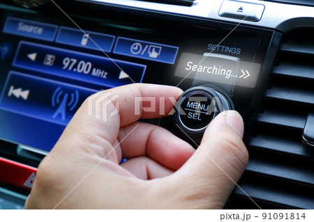 The driver adjusts his hand to seek for a radio station on the automobile radio dashboard 91091814