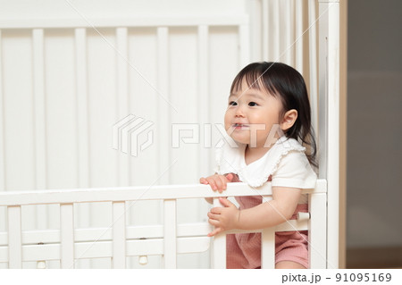ベビーベッドの中で遊ぶ1歳の女の子 91095169