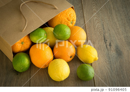 Many fruits falling out from paper package on brown wooden background Many fruits falling out from paper package on brown wooden background 91096405