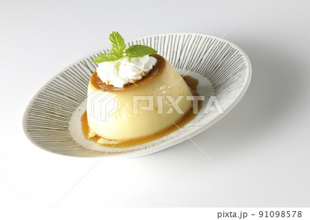 平らなお皿にに盛り付けてある生クリーム、ミントの葉が乗った昔ながらのレトロプリンを白背景で撮影 91098578