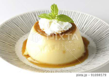 平らなお皿にに盛り付けてある生クリーム、ミントの葉が乗った昔ながらのレトロプリンを白背景で撮影 91098579
