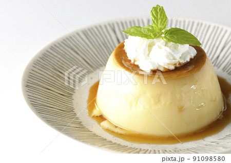 平らなお皿にに盛り付けてある生クリーム、ミントの葉が乗った昔ながらのレトロプリンを白背景で撮影 91098580
