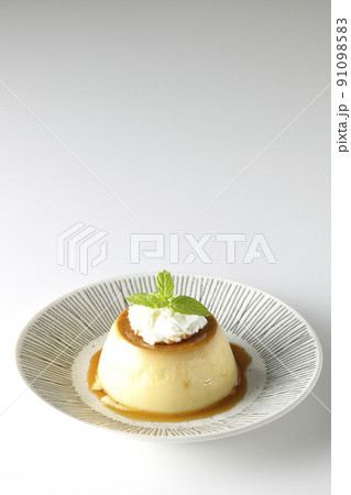 平らなお皿にに盛り付けてある生クリーム、ミントの葉が乗った昔ながらのレトロプリンを白背景で撮影 91098583