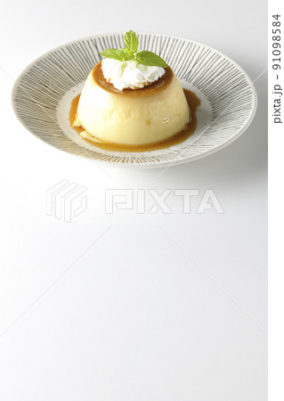 平らなお皿にに盛り付けてある生クリーム、ミントの葉が乗った昔ながらのレトロプリンを白背景で撮影 91098584