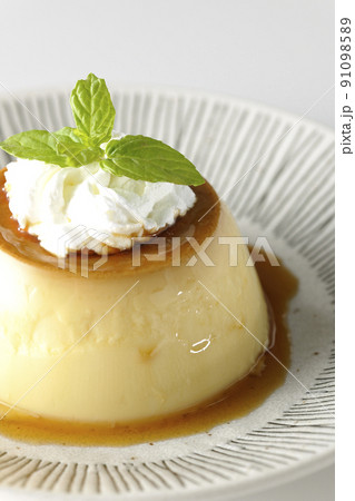 平らなお皿にに盛り付けてある生クリーム、ミントの葉が乗った昔ながらのレトロプリンを白背景で撮影 平らなお皿にに盛り付けてある生クリーム、ミントの葉が乗った昔ながらのレトロプリンを白背景で撮影 91098589
