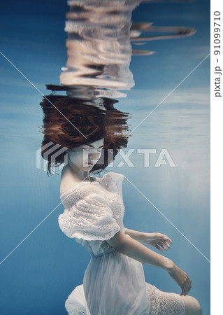 A girl in a dress with lace swims underwater as if in zero gravity 91099710