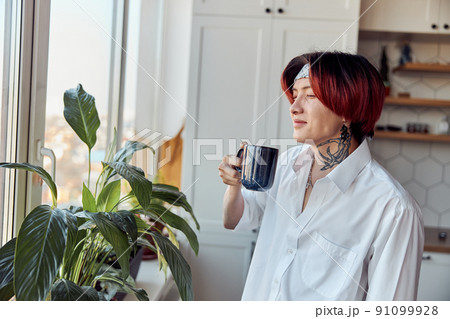 Happy Asian guy closing his eyes and enjoying coffee near the window 91099928