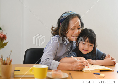 Loving mature grandma helping little grandchild doing homework. Multi generational, family and love concept Loving mature grandma helping little grandchild doing homework. Multi generational, family and love concept 91101114