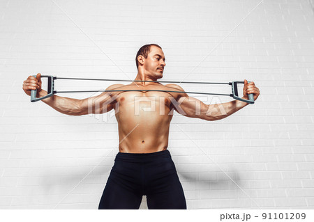 Handsome young sportsman exercising using expander while standing against white background 91101209