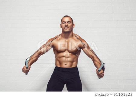 Handsome young sportsman exercising using expander while standing against white background 91101222