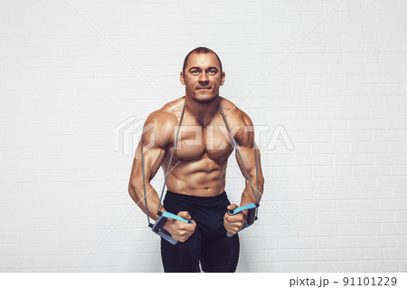 Handsome young sportsman exercising using expander while standing against white background 91101229