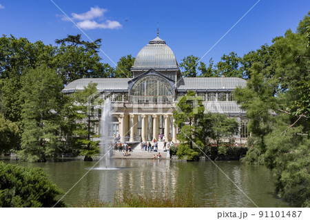 Crystal Palace. Building located in the Retiro Park in Madrid with its glass windows surrounded by trees and green vegetation on a sunny day and some clouds in the sky, in Spain. Europe. Photography. Crystal Palace. Building located in the Retiro Park in Madrid with its glass windows surrounded by trees and green vegetation on a sunny day and some clouds in the sky, in Spain. Europe. Photography. 91101487