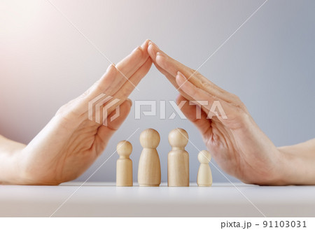 Woman hands under wooden models of family. 91103031
