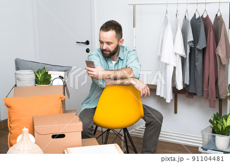 Mature man using mobile phone while unpacking things from boxes moving in new apartment. Mature man using mobile phone while unpacking things from boxes moving in new apartment. 91104481