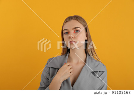 Beautiful model girl in autumn cloak on yellow background 91105168