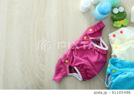 Concept of baby clothes with reusable diapers on wooden background 91105496