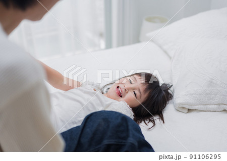 パパと一緒にベッドで遊ぶ小さな女の子 パパと一緒にベッドで遊ぶ小さな女の子 91106295
