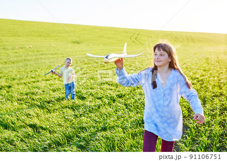 Cheerful and happy children play in the field and imagine themselves to be pilots on a sunny summer day. Kids dreams of flying and aviation. Cheerful and happy children play in the field and imagine themselves to be pilots on a sunny summer day. Kids dreams of flying and aviation. 91106751