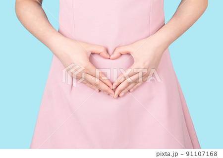 Close up of healthy woman hand made heart shape on her stomach. Concept of good digestive, healthy gut, probiotics, slim fit, gynecology and woman health care. 91107168