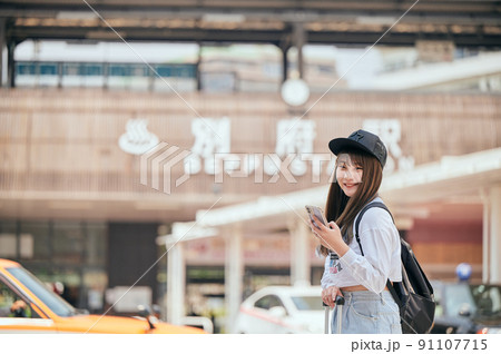 別府駅前でスマホを持って観光する若い女性 別府駅前でスマホを持って観光する若い女性 91107715
