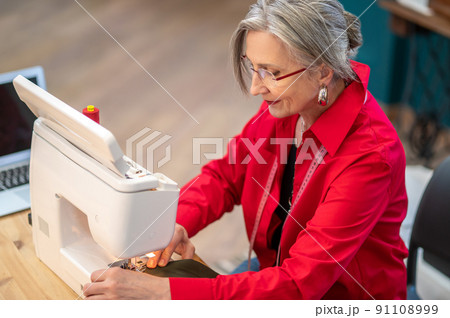 Top view of woman sewing on machine 91108999