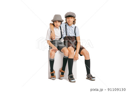 Two school age boys, stylish kids wearing retro clothes posing isolated over white background. Concept of childhood, vintage summer fashion style 91109130